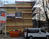 Gerüst an Hausfassade mit Firmenauto im Vordergrund